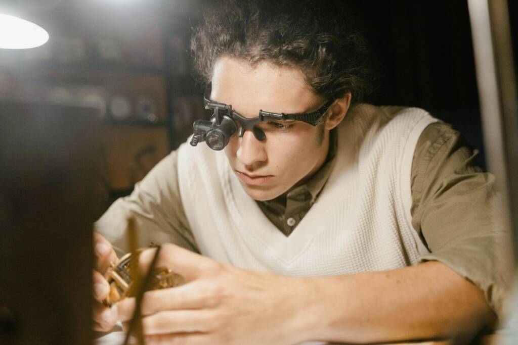 Jeune horloger réparant une montre avec loupe